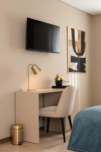 a desk with a chair and a television on a wall at Stella Braga Aparthotel in Braga