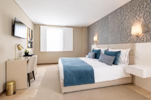 a bedroom with a large bed and a desk at Stella Braga Aparthotel in Braga