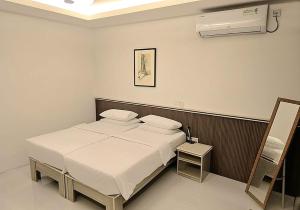 a bedroom with a white bed and a air conditioner at Foavahi Shark View Inn in Fuvahmulah