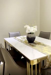 una mesa con un jarrón con flores blancas. en Lacasa Homes, en Kampala