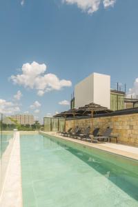 a swimming pool with chairs and a building at Las Brisas Merida in Mérida