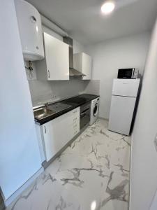 eine Küche mit weißen Schränken, einer Spüle und einem Kühlschrank in der Unterkunft Precioso Apartamento Santa Cruz in Santa María de Gracia