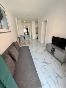 ein Wohnzimmer mit einem Sofa und einem TV auf einem Marmorboden in der Unterkunft Precioso Apartamento Santa Cruz in Santa María de Gracia