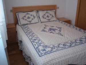 a bed with a blue and white comforter and pillows at Jardín de Boiro in Boiro