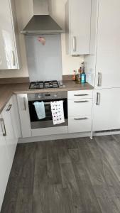 a kitchen with white cabinets and a stove top oven at Two bedroom coach house in brooklands - MK in Milton Keynes
