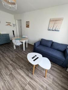 ein Wohnzimmer mit einem blauen Sofa und einem Tisch in der Unterkunft Appartement proche de la plage in Gravelines