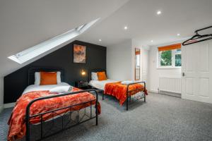 two beds in a room with black walls and orange sheets at Modern Comfort 4BR Home for 10 in North Weald