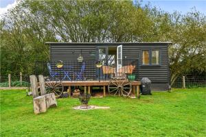 una pequeña casa negra con terraza de madera en Badger Shepherds Hut, en Hartfield