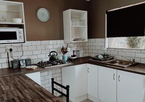 a kitchen with white cabinets and a sink and a microwave at Livingwaters Self-Catering Accommodation in Ermelo