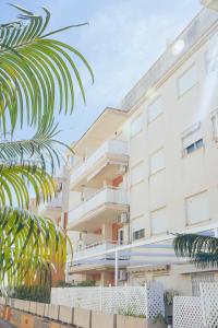 a white building with a palm tree in front of it at Blanca Mar in Barrio-Mar