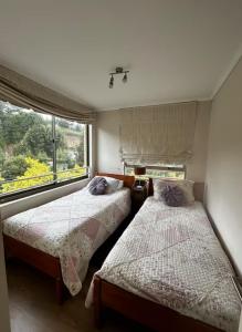 two beds in a room with a window at Departamento en Pingueral, Vista Maravillosa in Dichato
