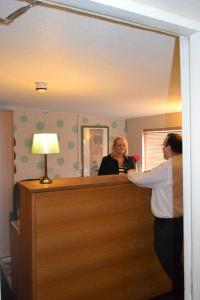 Un uomo e una donna in piedi davanti a uno specchio di Ambrose Hotel a Barrow in Furness