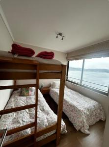 two bunk beds in a room with a window at Departamento en Pingueral, Vista Maravillosa in Dichato