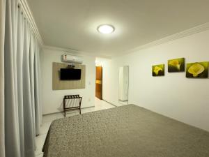 ein Schlafzimmer mit einem Bett und einem Fernseher an der Wand in der Unterkunft Annamar Hotel in João Pessoa