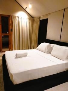 a bedroom with a large bed with white sheets and pillows at Enchanted Escapes Yala in Kirinda