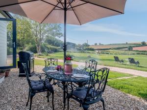 a table with chairs and an umbrella on a patio at 2 Bed in Cheriton Fitzpaine 78468 in Cheriton Fitzpaine