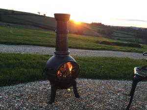 a black stove sitting on the ground with the sunset in the background at 2 Bed in Cheriton Fitzpaine 78468 in Cheriton Fitzpaine