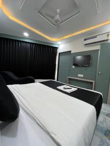 a bedroom with a large white bed with a flat screen tv at Hotel Golden Park in Ahmedabad