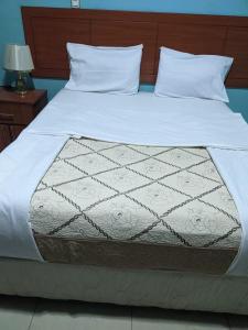 a large bed with white sheets and pillows at Glory Motel by HODAC LTD in Kigali