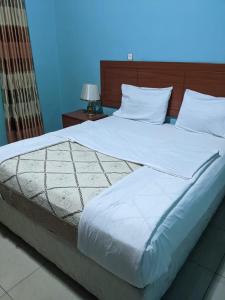 a large bed with white sheets and pillows at Glory Motel by HODAC LTD in Kigali