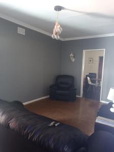 a living room with a leather couch and a chair at KHAHILIGI Guest House in Roodepoort