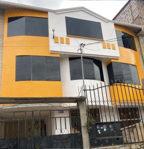 a yellow and white building with black windows at Residencia Lolita, tu hogar en Loja in Loja
