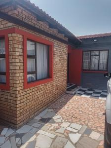 a house with a brick wall and two windows at KHAHILIGI Guest House in Roodepoort