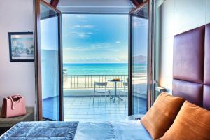 a bedroom with a bed and a view of the ocean at Hotel La Battigia in Alcamo Marina