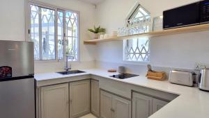 cocina con encimeras blancas, fregadero y nevera en Mermaid Cove - GARDEN, en Blue Bay