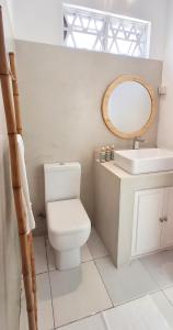 Un baño con inodoro, lavabo y espejo. en Mermaid Cove - GARDEN, en Blue Bay 4 fotos más