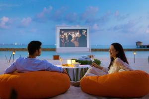 un homme et une femme assis dans des poufs sur la plage dans l'établissement Centara Ras Fushi Resort & Spa Maldives - 50 percent discount on transfers for min 4 nights stay and more, valid for reservations between 11th Feb till 22 Dec 2025, à Atoll Malé Nord