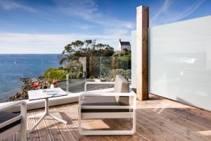 een balkon met een tafel en stoelen en de oceaan bij Relais & Châteaux Le Brittany & Spa in Roscoff