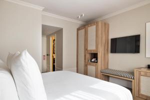 une chambre avec un lit blanc et une télévision à écran plat dans l'établissement One Shot La Latina, à Madrid 4 autres photos