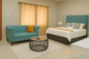 a bedroom with a bed and a blue couch at Bear Haven Lodge in Manguzi