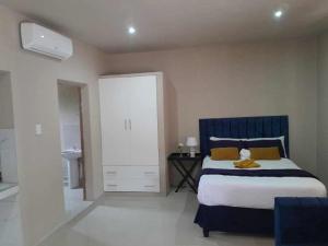 a bedroom with a blue and white bed and a bathroom at Bear Haven Lodge in Manguzi