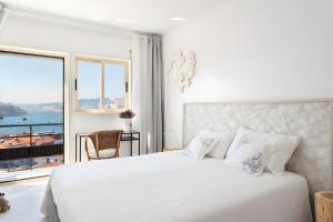 a white bedroom with a large bed and a window at Vegan Topfloor - Douro e Ribeira in Bandeira