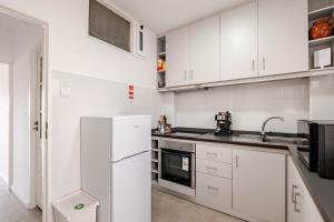 a kitchen with white cabinets and a refrigerator at Vegan Apartment - Porto e Douro in Bandeira