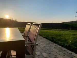 two chairs and a table on a patio with the sunset at Ferienwohnungen Joachim Fischer in Vaihingen an der Enz