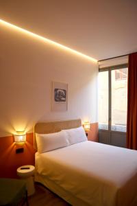 a bedroom with a bed with two lamps and a window at Aparthotel Casa Fages in Figueres