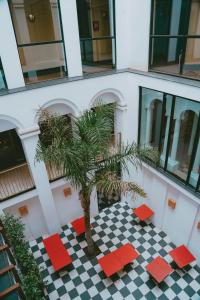a palm tree in front of a building with red chairs at Aparthotel Casa Fages in Figueres