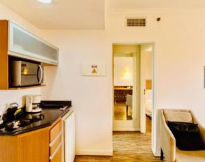 a kitchen with a counter top and a living room at Studio Completo - Vila Olímpia - Moema in São Paulo