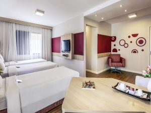a hotel room with two beds and a table at Mercure Sao Paulo Alamedas in Sao Paulo