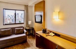 a hotel room with a couch and a phone at Studio Completo - Vila Olímpia - Moema in Sao Paulo