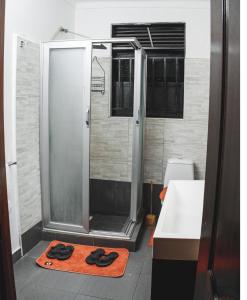 a bathroom with a shower with a pair of slippers at A&z apartments in Namulanda