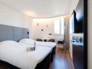 a hotel room with two beds and a tv at ibis Beziers Est Mediterranee A9/A75 in Béziers