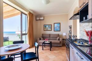 a kitchen and living room with a couch and a table at I Faraglioni Comfort Rooms in Terrasini