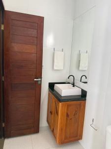 a bathroom with a sink and a wooden door at Apartamentos Ventos da Sibauma in Tibau do Sul +35 photos