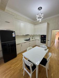 a kitchen with a white table and a black refrigerator at 2-Bedroom Apartment in Sumqayyt