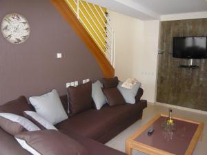 a living room with a brown couch and a table at Gîte moderne à Rebeuville, proche Neufchâteau, 3 ch., accès PMR, pêche, WIFI, tout inclus - FR-1-589-157 in Rebeuville