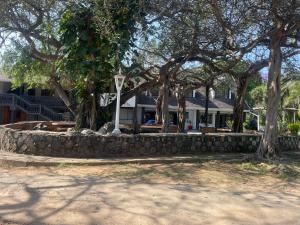 a stone wall in front of a house with trees at North Coast Gateway Hotel in KwaMbonambi